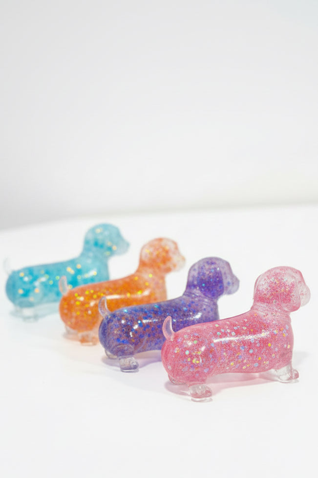 Four glitter squishy wiener dogs in pink, orange, purple, and blue